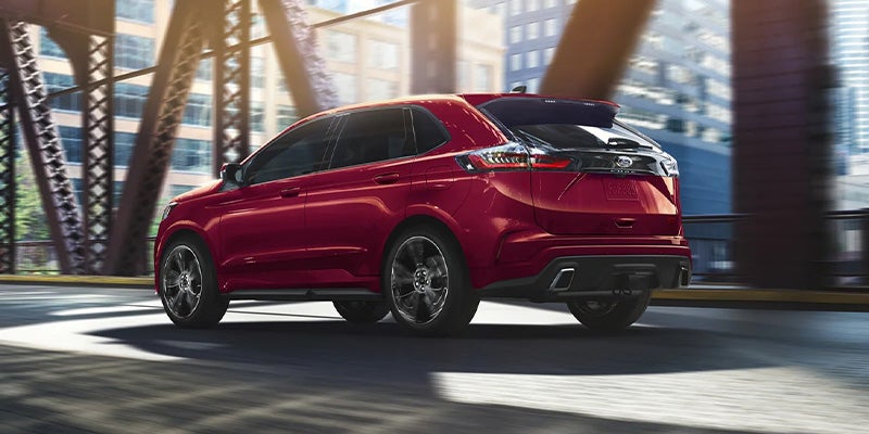 Red hybrid Ford SUV driving on bridge