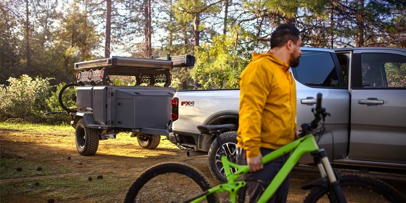 Ford Ranger in the background with trailer and next to two bikes and a man